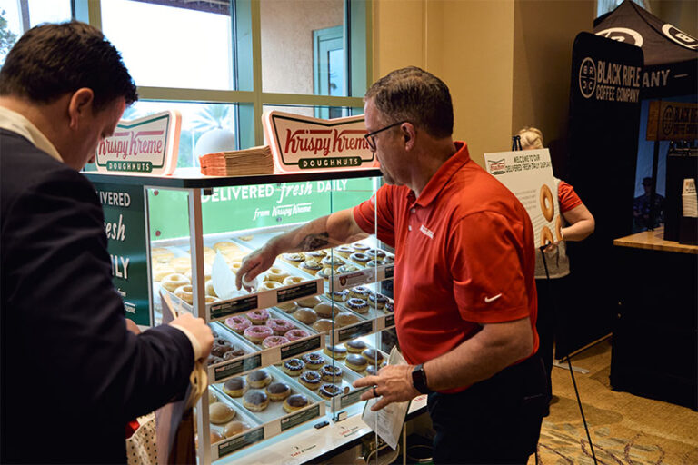 Man grabbing a Krispy Kreme doughnut out of a case